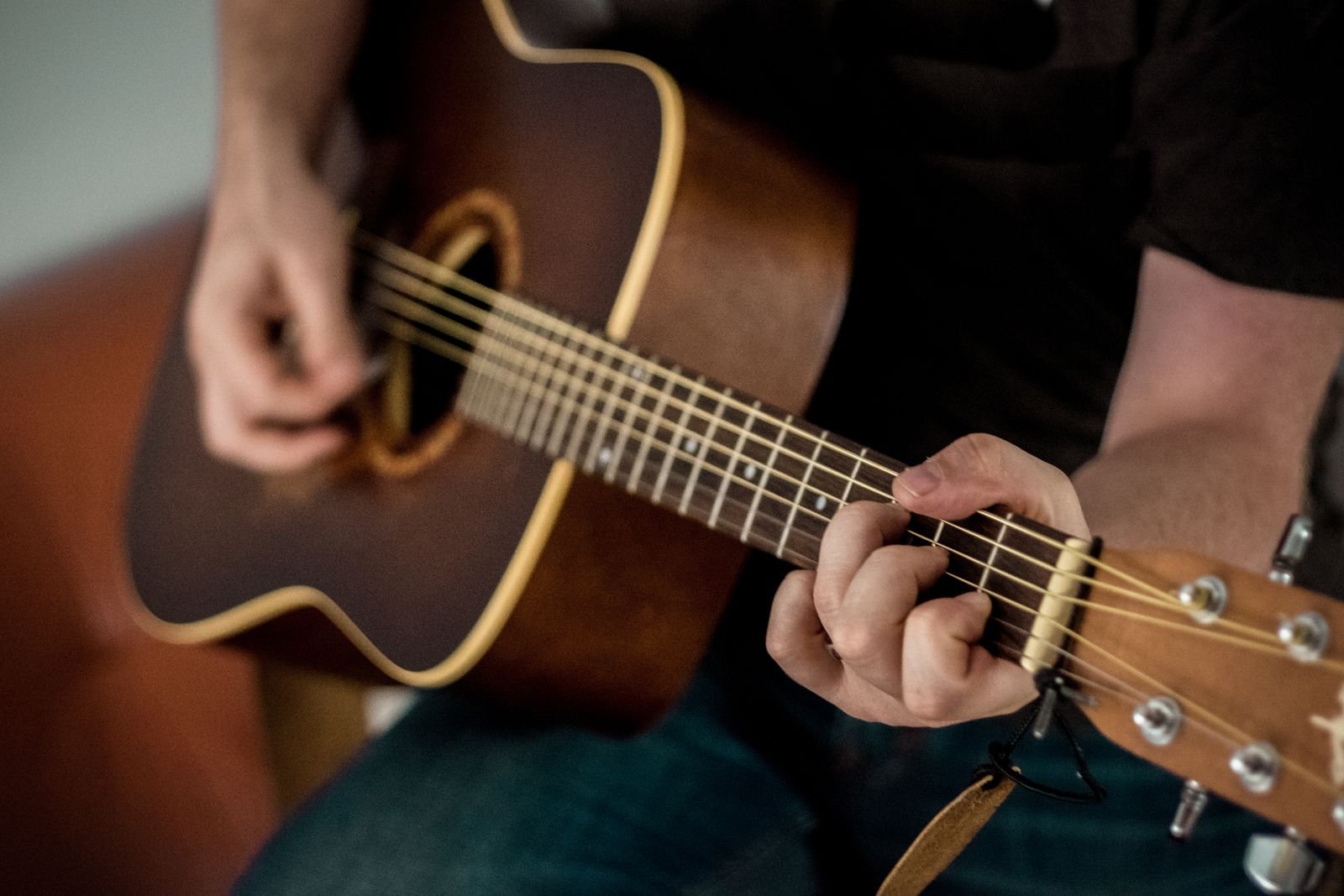 An acoustic guitar being played in warm, intimate light
