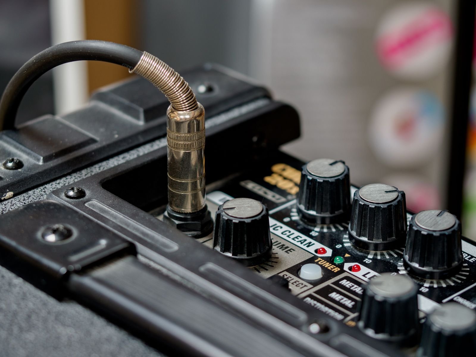 Close-up of a guitar amplifier and multi-effects unit with knobs and a coiled cable