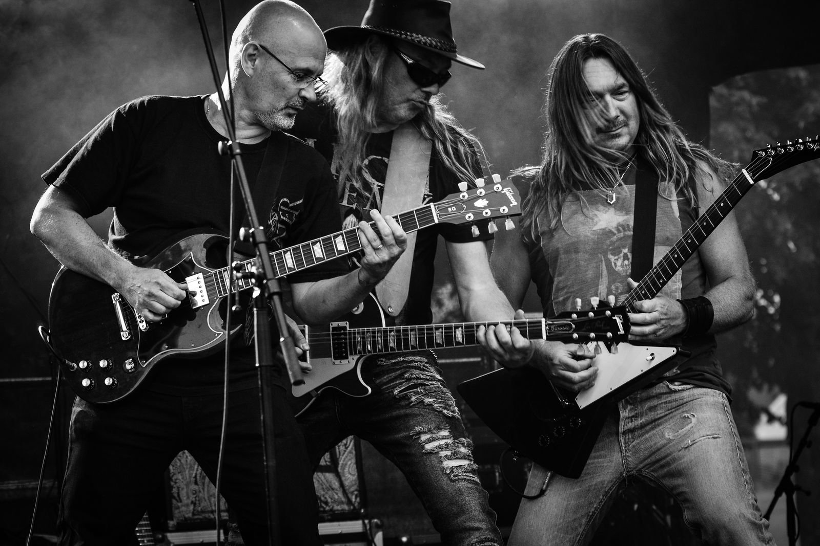 Three guitarists playing a gritty, low-lit club show in black and white