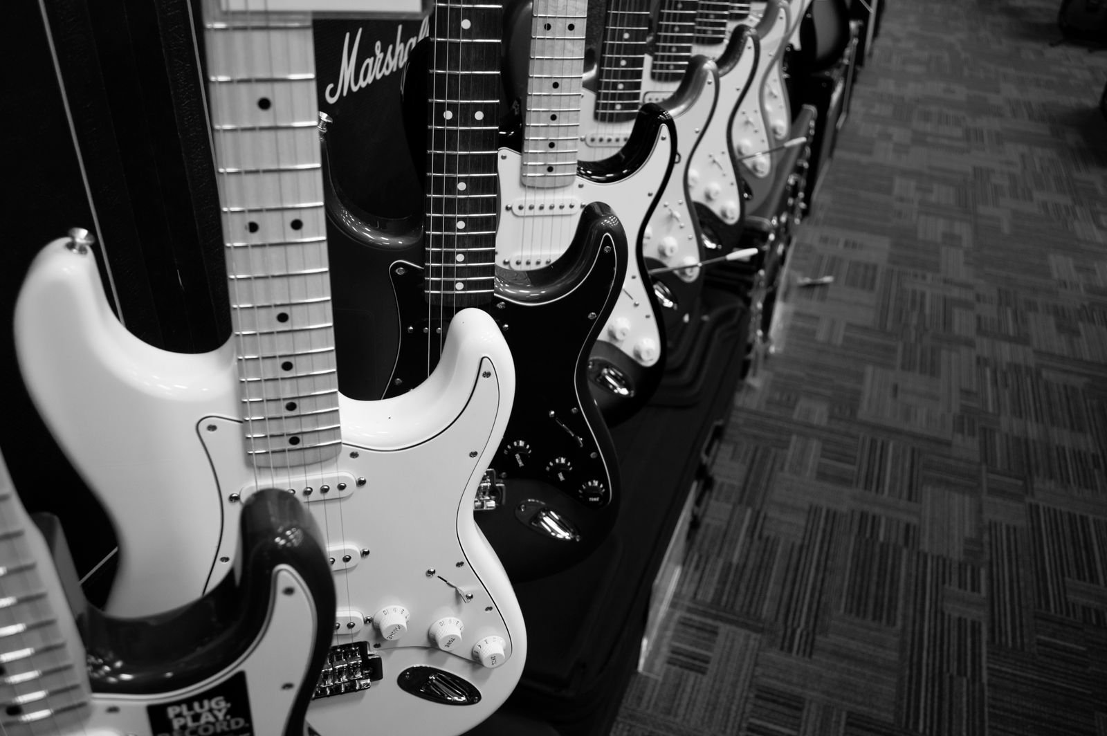 A black-and-white wall of electric guitars hanging in a music shop