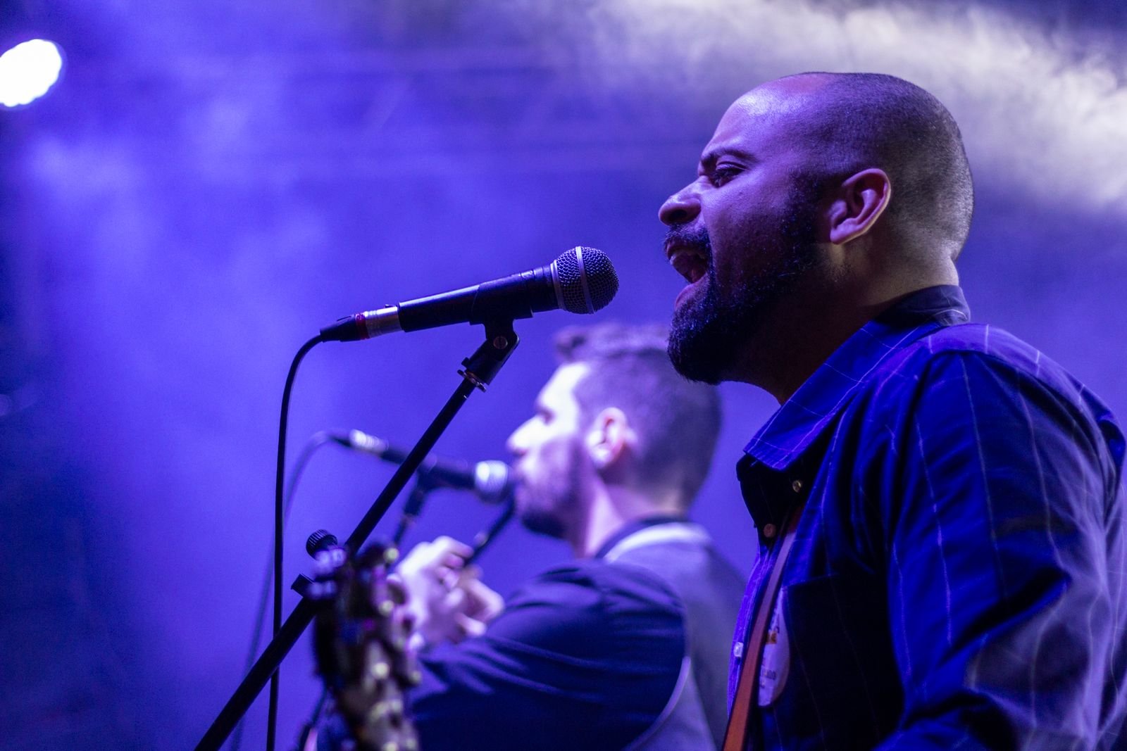 A singer leaning into a microphone under stage lights